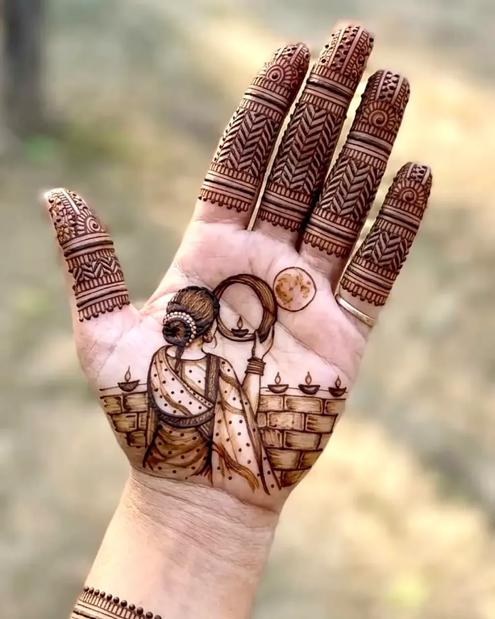 Karwa Chauth mehndi design with a woman looking at the moon through a chhalni with diyas on the palm